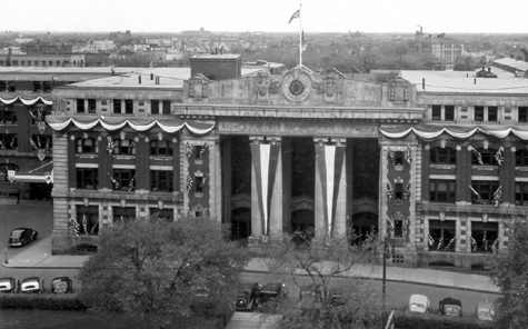a black and white aerial photo of 181 Higgins pillar doors, 19th century, The pillars have banners over them, and the building is decorated.