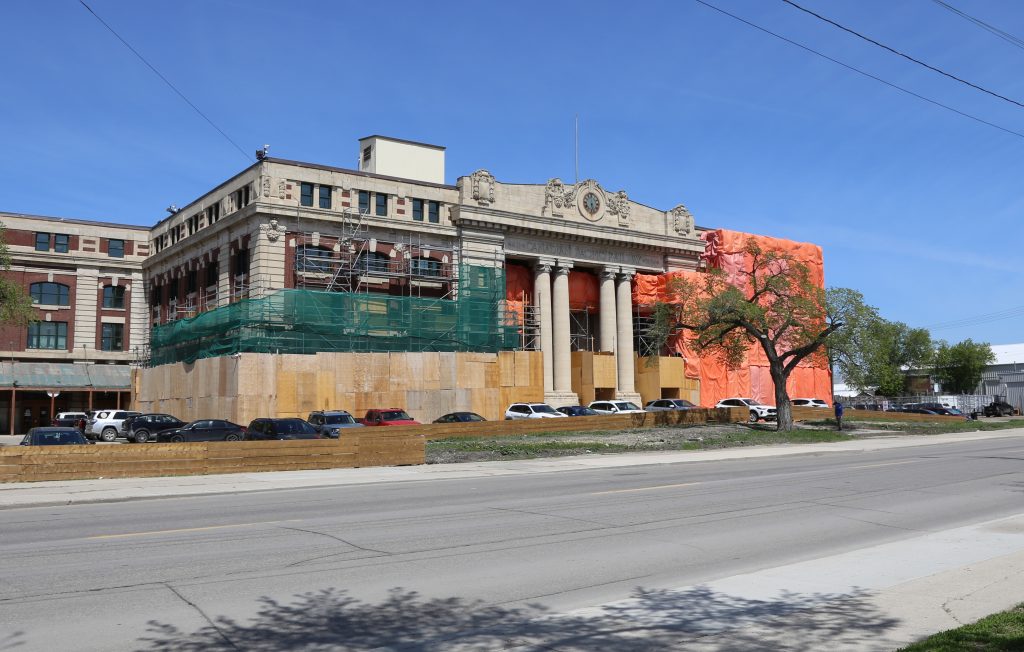 A photo of 181 Higgins undergoing renovations and upgrades. Orange tarps are covering half of the building.