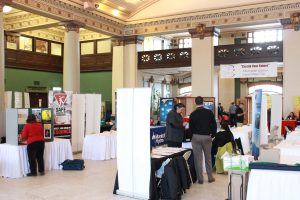 The rotunda within 181 Higgins, populated with tables and chairs for an event. Photo includes career fair activity.