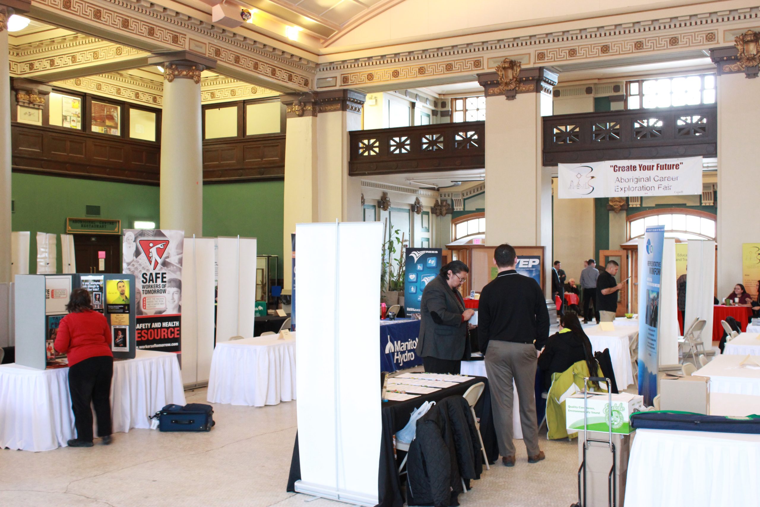 The rotunda within 181 Higgins, populated with tables and chairs for an event. Photo includes career fair activity.